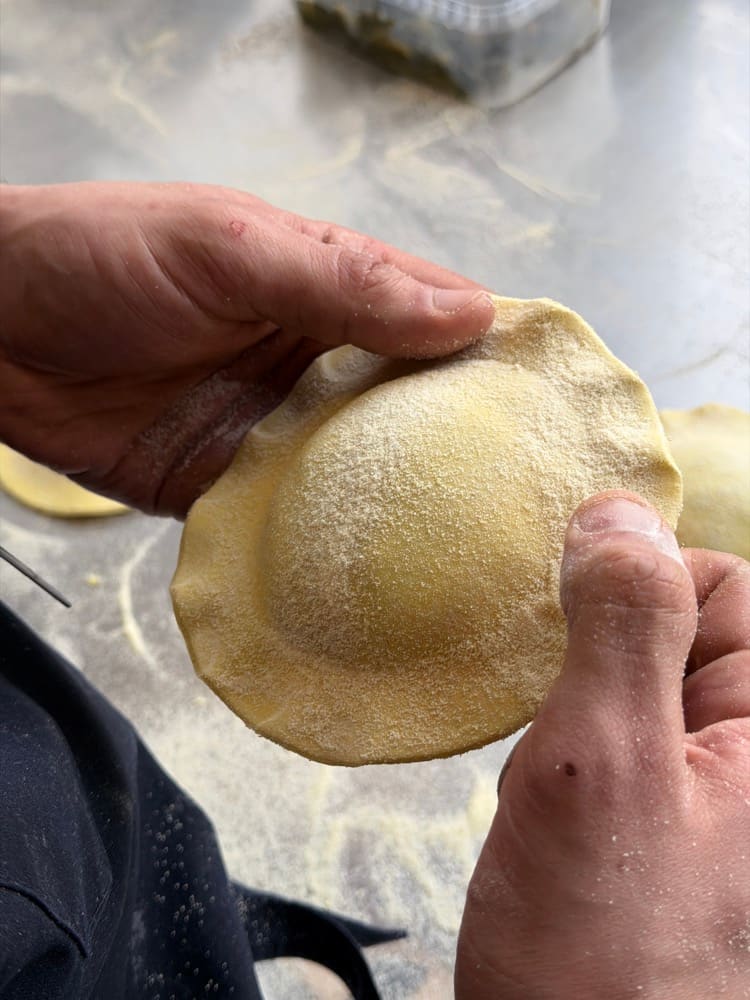 Hands folding a large raviolo